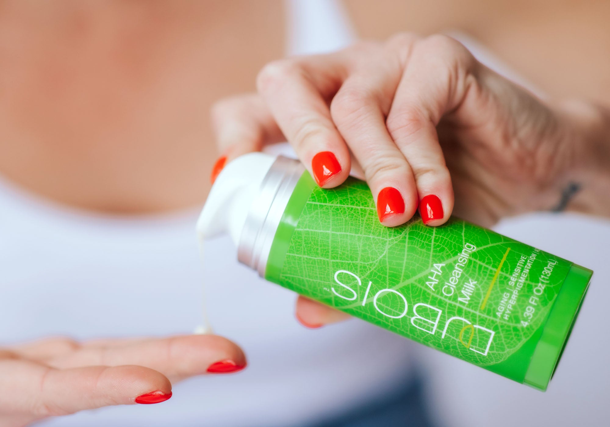 woman pumping aha cleansing milk onto finger