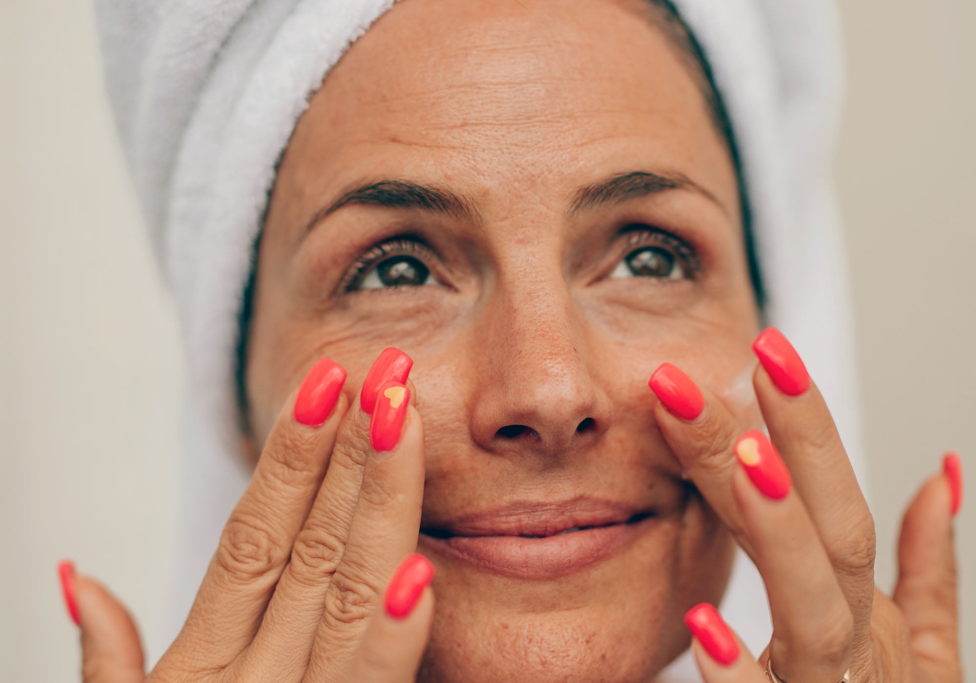 Woman putting antioxidant serum on cheeks