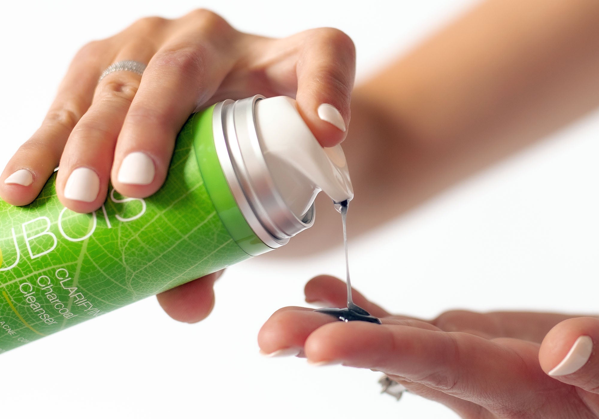 Woman pumping charcoal cleanser onto fingers