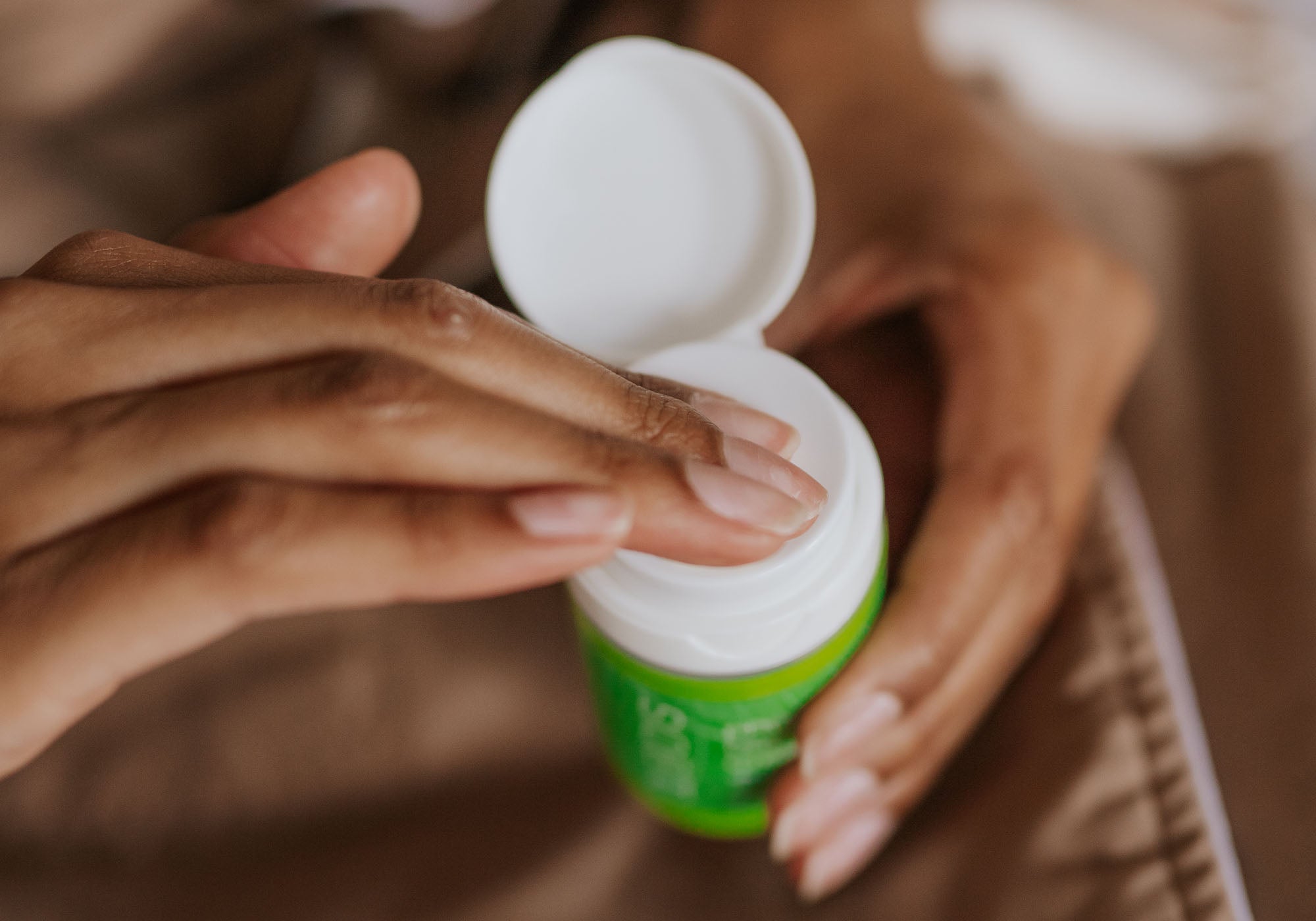 woman putting day cream on fingers