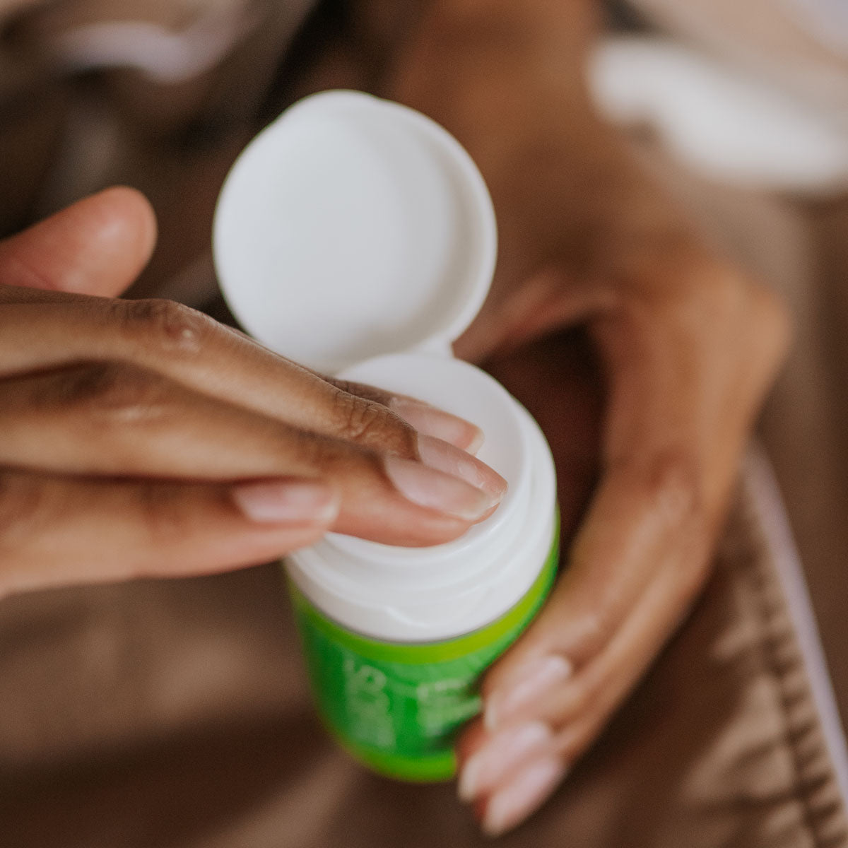 woman putting fingers in restorative night cream bottle