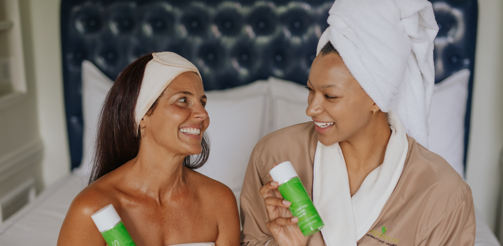 two women holding skincare products and smiling