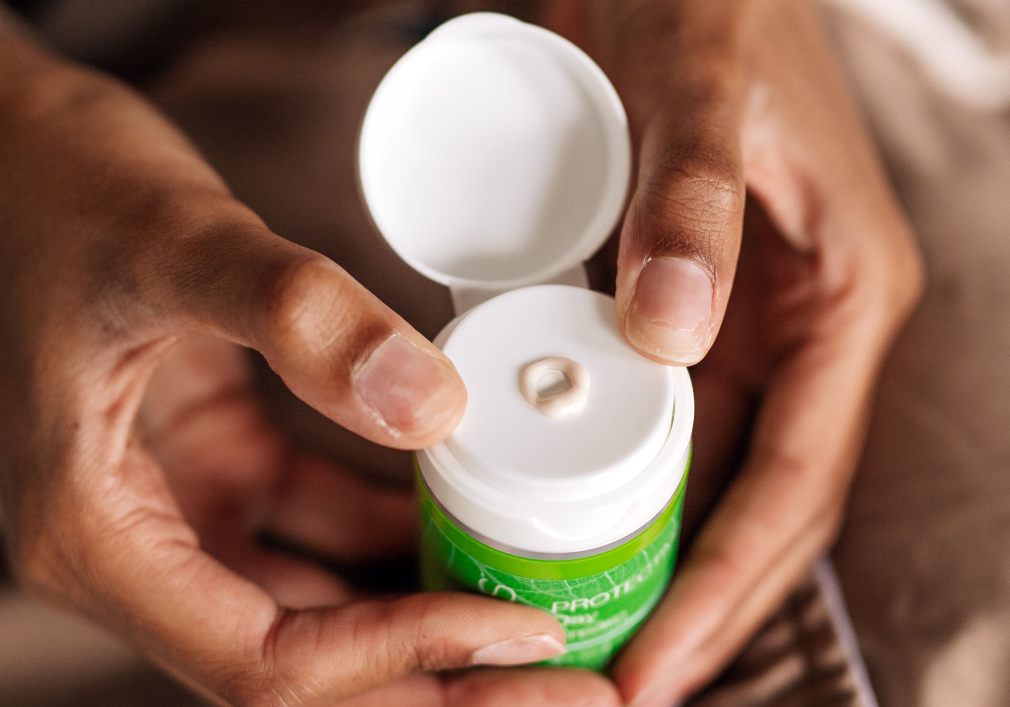 Woman holding open bottle of day cream