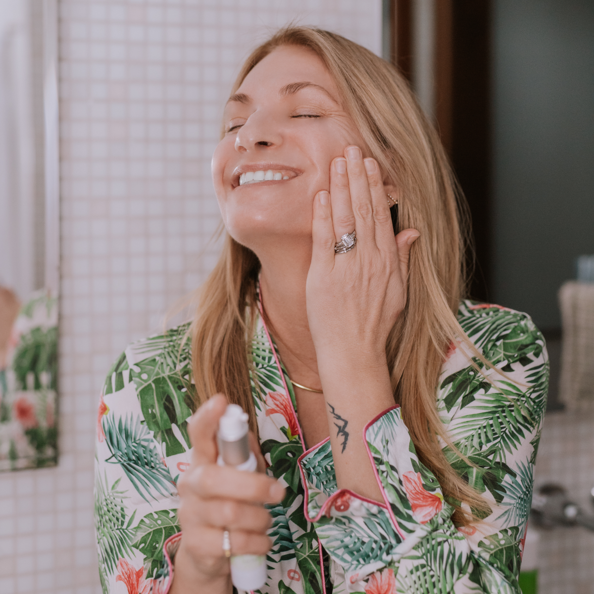 woman smiling and applying serum