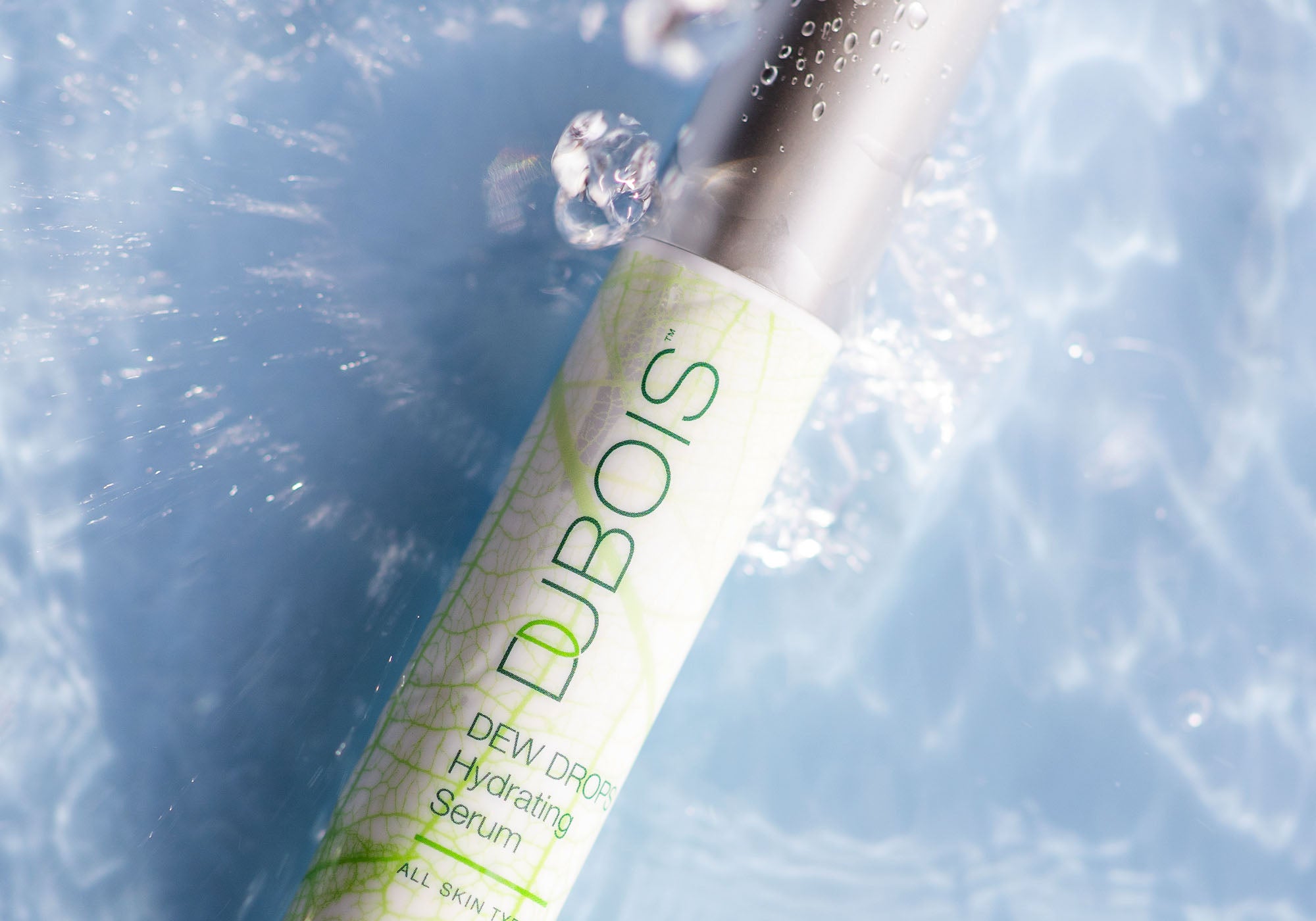 Tube of Dew Drops Hydrating Serum falling into water with water drops