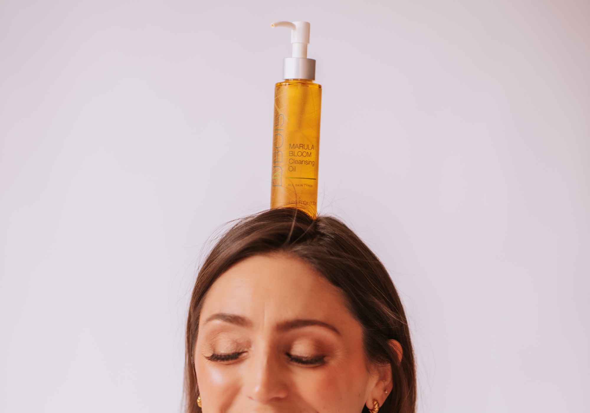 woman with oil cleanser balanced on her head